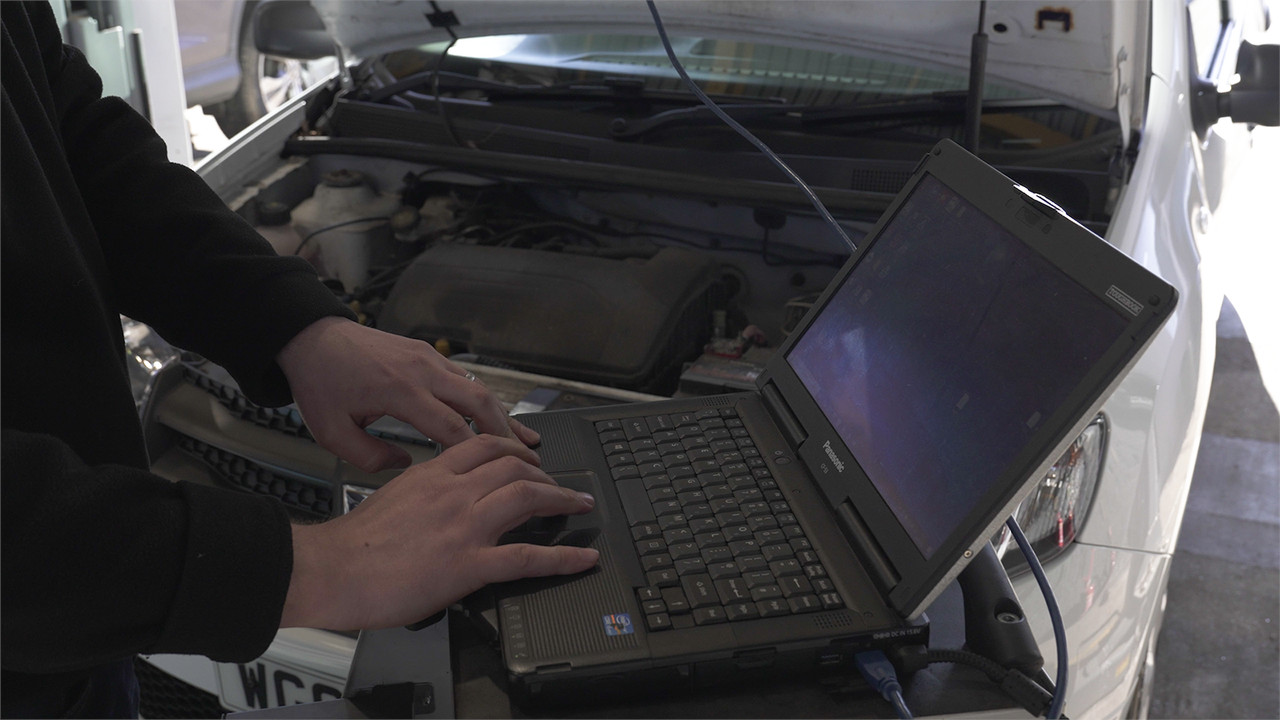 mechanic with laptop plugged into car