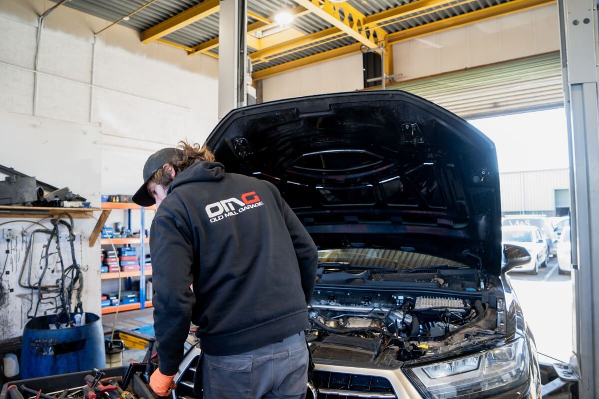 mechanic with old mill garage jumper working on car