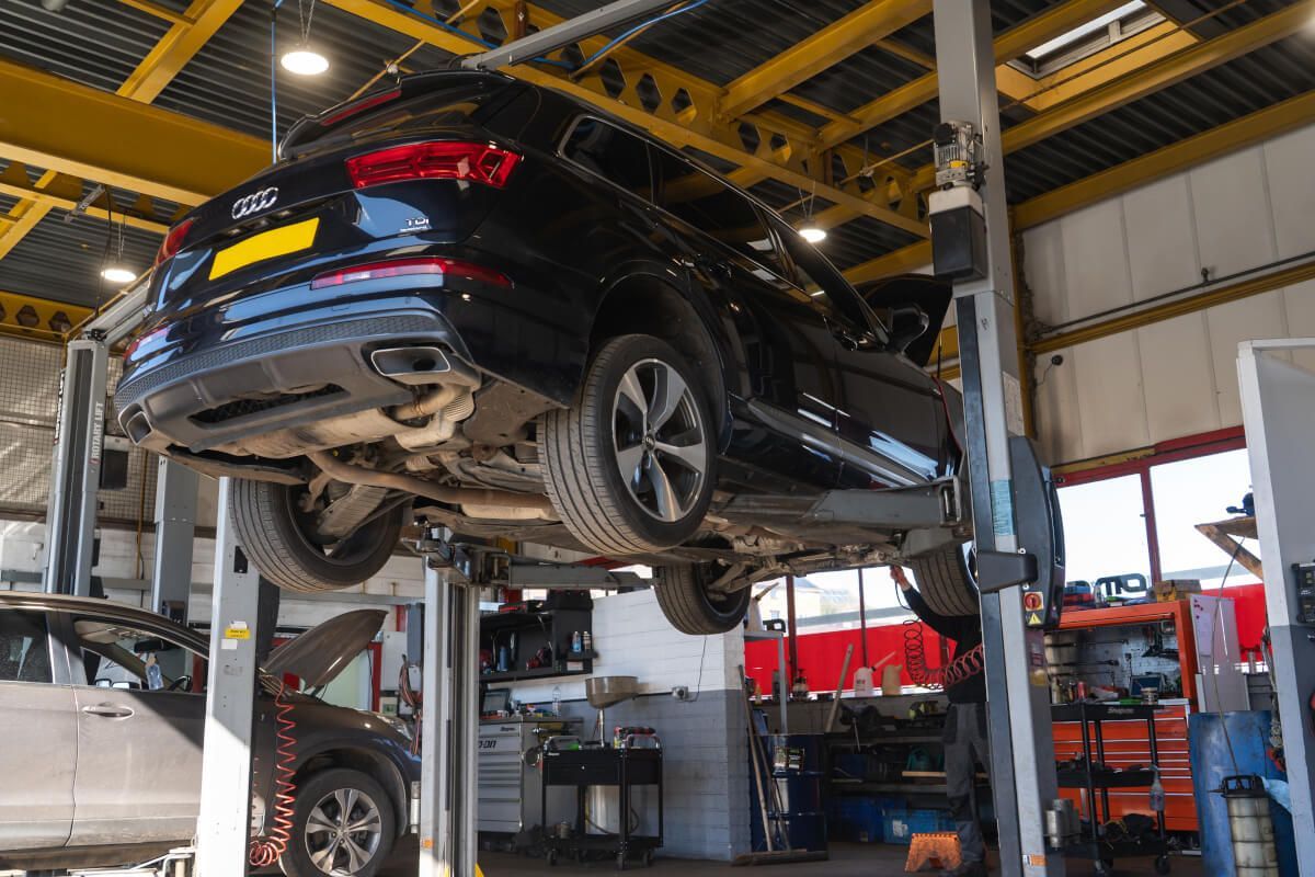 car up on stands with mechanic working at the front
