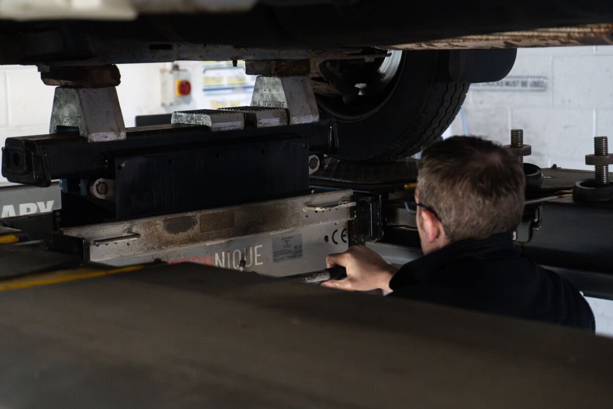 mechanic under car checking wheels