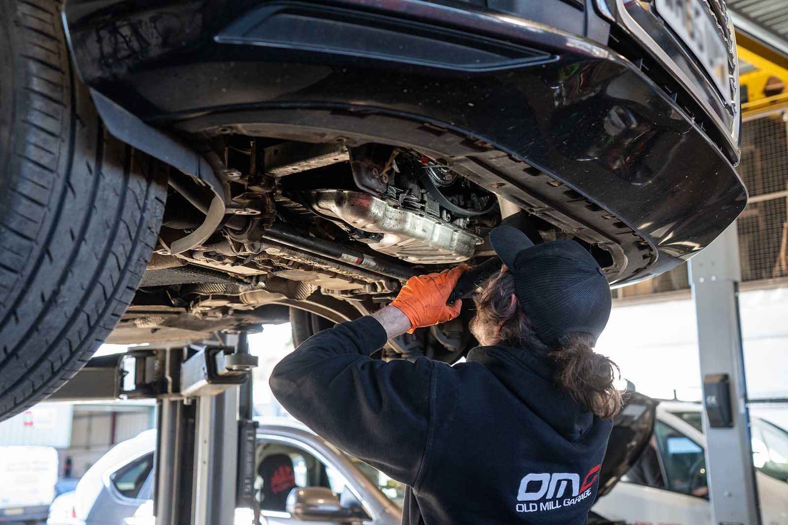 mechanic with a touch investigating under car in garage